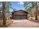 A two-car garage made of wood with a concrete driveway, surrounded by lush trees at 20425 Flint Ln, Morrison, CO 80465