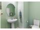 Charming half-bathroom features a pedestal sink, round mirror, and soft green walls, offering a fresh feel at 1190 Telleen Ave, Erie, CO 80516