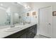 Bright bathroom featuring double sinks, dark wood cabinets, quartz countertops, and a large mirror at 1190 Telleen Ave, Erie, CO 80516