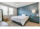 Cozy bedroom with a large window, blue accent wall, white bedding, and natural light at 1190 Telleen Ave, Erie, CO 80516