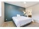 Comfortable bedroom featuring a blue accent wall, white bedding, and a view into the en-suite bathroom at 1190 Telleen Ave, Erie, CO 80516