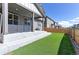 Inviting backyard with artificial turf, steps to covered patio, grill, and wood fence at 9835 Uravan St, Commerce City, CO 80022