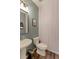 Stylish powder room features modern geometric wallpaper, pedestal sink, and decorative mirror at 9835 Uravan St, Commerce City, CO 80022