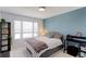 Cozy bedroom featuring a stylish blue accent wall and natural light from the window at 9835 Uravan St, Commerce City, CO 80022