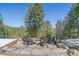 Stone patio with outdoor chairs surrounding a fire pit; mountain views and evergreen trees in background at 22683 Hagler Dr, Golden, CO 80401