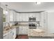 Well-lit kitchen boasts stainless steel appliances, granite countertops and sleek white cabinetry at 9940 Pecos St, Thornton, CO 80260