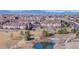 View of multi-story townhouses with mature trees overlooking a small pond with walking paths and mountain views at 12783 Leyden St # E, Thornton, CO 80602