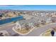 Aerial view of green multi-story townhouses near a pond and open space, with mountain views in the background at 12783 Leyden St # E, Thornton, CO 80602