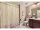 This bathroom features a shower with curtain, a toilet, and vanity with a dark wood base at 6614 Club Villa Rd, Parker, CO 80134