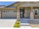 Home exterior showcasing a two-car garage, stone accents, front yard landscaping, and a covered front porch at 6614 Club Villa Rd, Parker, CO 80134