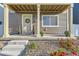 Close-up of the front porch, showing decorative plants, stone ground cover, a welcoming wreath on the door, and concrete steps at 18270 E 51St Pl, Denver, CO 80249