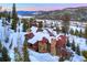 Aerial view of snow covered neighborhood home surrounded by tall pine trees and mountains at 118 Gold Piece Dr, Breckenridge, CO 80424