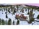 Expansive aerial view of a luxury home surrounded by snow-covered trees and distant mountain peaks at 118 Gold Piece Dr, Breckenridge, CO 80424