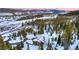 Majestic estate nestled amidst snow-covered forest with a striking red roof and mountain views at 118 Gold Piece Dr, Breckenridge, CO 80424