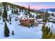 Aerial view of snow covered neighborhood home surrounded by tall pine trees and mountains at 118 Gold Piece Dr, Breckenridge, CO 80424
