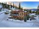 Stone house with a red roof, large windows, and an outdoor fireplace, set against a backdrop of snow-covered mountains at 118 Gold Piece Dr, Breckenridge, CO 80424