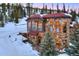 Grand stone home with snow, a red roof, and large windows offering beautiful natural light at 118 Gold Piece Dr, Breckenridge, CO 80424