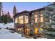 Stone home with a wall of windows, snowy landscape, and exterior lanterns, offering a cozy and inviting ambiance at 118 Gold Piece Dr, Breckenridge, CO 80424