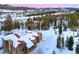 Stunning snow-covered mountain home with a red roof and stone chimney against a breathtaking scenic backdrop at 118 Gold Piece Dr, Breckenridge, CO 80424
