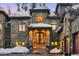 Close up of an impressive stone home featuring a grand entrance with black doors and manicured landscaping in snow at 118 Gold Piece Dr, Breckenridge, CO 80424