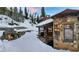 Stone house with an outdoor fireplace, and balcony, surrounded by snow-covered landscape and evergreen trees at 118 Gold Piece Dr, Breckenridge, CO 80424