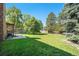 Expansive backyard with a grassy lawn, mature trees, and a patio area at 10247 W Roxbury Pl, Littleton, CO 80127