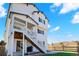 Rear exterior view of a two-story home with a white exterior, black trim, staircase leading to a balcony and backyard at 1044 Oleander St, Castle Rock, CO 80109