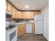 Efficient kitchen with wood cabinets, stone backsplash, and white appliances at 1390 N Emerson St # 105, Denver, CO 80218