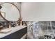 Stylish bathroom featuring marble countertops, a round mirror, and contemporary fixtures at 10689 Shadow Pines Rd, Parker, CO 80138