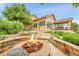 Fire pit and outdoor living space with manicured landscaping and a glimpse of the lake at 26631 E Arbor Dr, Aurora, CO 80016