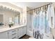 Bright bathroom featuring dual sinks, a large mirror and a shower-over-tub with a patterned curtain at 3968 Ashcroft Ave, Castle Rock, CO 80104