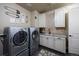 Laundry room with stainless steel washer and dryer, cabinetry, sink, and decorated walls at 10601 Montecito Dr, Lone Tree, CO 80124