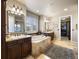 Well-lit main bathroom with tiled floors, soaking tub, separate vanities, and walk-in closet at 10601 Montecito Dr, Lone Tree, CO 80124