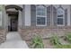 Home entrance featuring a stone facade, arched doorway, and manicured landscaping with a concrete walkway at 6612 N Ceylon St, Denver, CO 80249