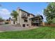 Rear exterior of a home with an expansive lawn, covered patio, and stone accents at 8188 S Yukon St, Littleton, CO 80128