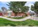 Community center featuring brick siding, grass, a patio, a pedestrian walkway, and mature trees at 12662 W Virginia Ave, Lakewood, CO 80228