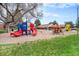 Community playground surrounded by grass with slides, play equipment, and a large shade tree at 12662 W Virginia Ave, Lakewood, CO 80228