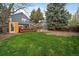 A spacious backyard features green grass, a deck, a sauna, and a two-story blue home at 8508 Vivian Ct, Arvada, CO 80005