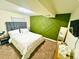 Stylish bedroom featuring a modern green accent wall and cozy white linens at 1528 Coronado Pkwy, Denver, CO 80229