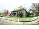 Corner lot home with gray siding, a red door, white picket fence, and mature landscaping enhancing curb appeal at 1528 Coronado Pkwy, Denver, CO 80229