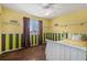 Bright bedroom featuring stylish striped walls, a window, shelves, ceiling fan, and comfortable furnishings at 11613 W Coal Mine Dr, Littleton, CO 80127