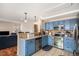 Bright kitchen with stainless steel appliances and blue cabinets adjacent to a living space at 11613 W Coal Mine Dr, Littleton, CO 80127