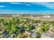 Panoramic view of homes in a neighborhood with mature trees and nearby commercial buildings under a clear blue sky at 3055 Carson St, Aurora, CO 80011