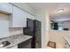 Updated kitchen featuring granite countertops, white cabinets, and black appliances, and an adjacent entry door at 2280 S Oswego Way # 104, Aurora, CO 80014
