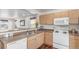 Functional kitchen with light wood cabinets, white appliances and an open view to the living area at 5530 Lewiston Ct, Denver, CO 80239