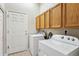 Bright laundry room with Whirlpool washer and dryer, wood cabinets, and white door at 2870 W Riverwalk Cir # B, Littleton, CO 80123