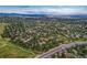 Expansive aerial view of a tree-lined suburban community with mountain views in the distance on a bright day at 6973 Daventry Pl, Castle Pines, CO 80108