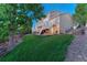 Spacious backyard features a lush lawn, mature trees, and a multi-level deck perfect for outdoor entertaining at 6973 Daventry Pl, Castle Pines, CO 80108
