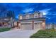 Charming two-story home with three-car garage and brick accents at twilight at 6973 Daventry Pl, Castle Pines, CO 80108