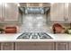 Close-up of a modern kitchen range with stainless steel hood and decorative backsplash tiles at 6973 Daventry Pl, Castle Pines, CO 80108